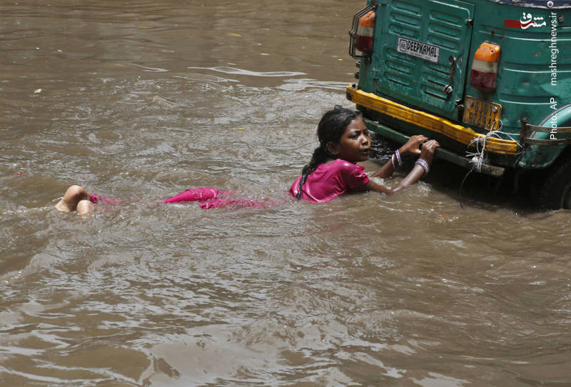 شنای تفریحی پشت یک خودرو پس از وقوع سیل در احمدآباد هند